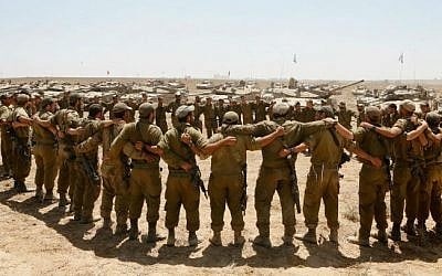 Israeli soldiers sing as they embrace each other at a staging area in southern Israel near the border with Gaza, as Israeli forces prepare to pull back from the area, on August 06, 2014. (Miriam Alster/Flash90)