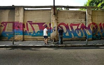 In this July 22, 2014 photo, 25-year old Lebanese graffiti artist, who goes by the art name Phat 2, right, and his friend Edgar, 15, speak after spray painting graffiti on abandoned shops in Beirut, Lebanon (photo credit: AP/Hussein Malla) 