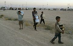 Displaced Iraqis from the Yazidi community carry humanitarian aid at the camp of Bajid Kandala at Feeshkhabour town near the Syria-Iraq border, in Iraq, Saturday, August 9, 2014. (AP/Khalid Mohammed)
