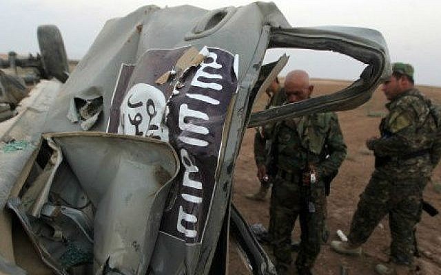 Peshmerga fighters inspect the remains of a car, bearing an image of the trademark jihadist flag, which belonged to Islamic State (IS) militants after it was targeted by an American air strike in the village of Baqufa, north of Mosul, on August 18,2014 (photo credit: AFP/Ahmad al-Rubaye) Peshmerga fighters inspect the remains of a car, bearing an image of the trademark jihadist flag, which belonged to Islamic State (IS) militants after it was targeted by an American air strike in the village of Baqufa, north of Mosul, on August 18,2014 (photo credit: AFP/Ahmad al-Rubaye)