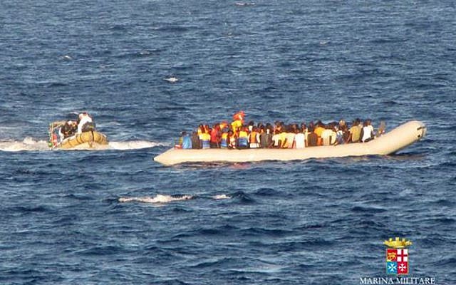 In this handout picture released by the Italian Navy on September 14, 2014 migrants sit in a boat during a rescue operation off the coast of Sicily. More than 2.000 migrants were rescued by Navy ships and patrol boats the last three days as part of the operation called Mare Nostrum. (photo credit: AFP/MARINA MILITARE)