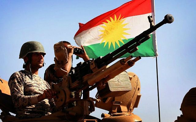 A flag of the autonomous Kurdistan region flies next to Iraqi Kurdish Peshmerga fighters standing on a tank on September 7, 2014. (photo credit: AFP/SAFIN HAMED) 