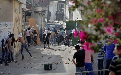 Palestinian youth take cover behind a wall as they hurl stones at Israeli policemen during a protest in the neighborhood of Wadi al-Joz in East Jerusalem on September 7, 2014. (photo credit: AFP/Ahmad Gharabli) Palestinian youth take cover behind a wall as they hurl stones at Israeli policemen during a protest in the neighborhood of Wadi al-Joz in East Jerusalem on September 7, 2014. (photo credit: AFP/Ahmad Gharabli)
