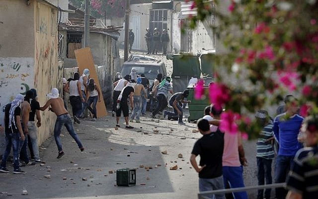 Palestinian youth take cover behind a wall as they hurl stones at Israeli policemen during a protest in the neighborhood of Wadi al-Joz in East Jerusalem on September 7, 2014. (photo credit: AFP/Ahmad Gharabli) Palestinian youth take cover behind a wall as they hurl stones at Israeli policemen during a protest in the neighborhood of Wadi al-Joz in East Jerusalem on September 7, 2014. (photo credit: AFP/Ahmad Gharabli)