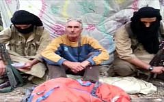 An image grab taken from a video released by Jund al-Khilafah via YouTube on September 22, 2014, allegedly shows French tourist, Herve Gourdel (center), sitting between two armed jihadists at an undisclosed location. (photo credit: AFP/HO/Jund al-Khilafah via YouTube)