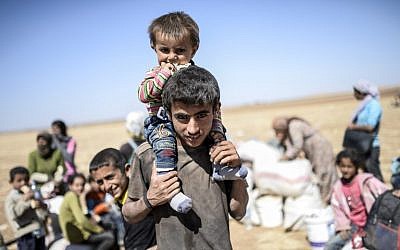 Syrian Kurds wait after they crossed the border near the the Syrian border in the southeastern town of Suruc in Sanliurfa province, on September 23, 2014. (photo credit: AFP/BULENT KILIC)