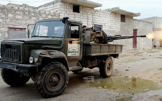 A file picture taken on January 27, 2014 shows an opposition fighter from the Ahrar al-Sham Brigade firing a machine gun from a truck displaying the group's flag during clashes with government forces as he defends the Marjah neighborhood of the northern Syrian city of Aleppo. (AFP/Mahmud al-Halabi/file)