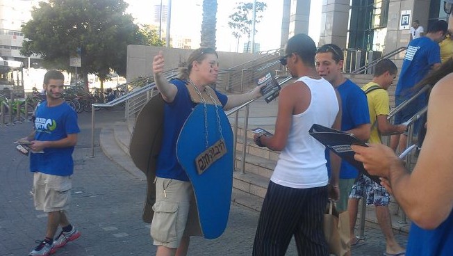 A Green Way activist dressed as the Kinneret offers free hugs to passersby during a demonstration on September 10. (photo credit: Melanie Lidman/Times of Israel)