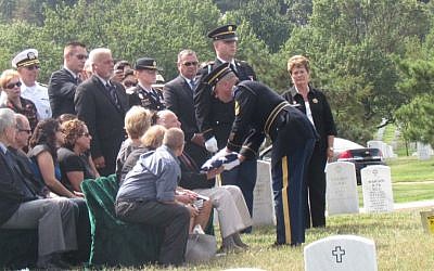 Sgt. Jason Lewis, a representative of the Army’s 3rd U.S. Infantry regiment, presents a flag to David Rogers, the nephew of Pfc. Bernard Gavrin, who died in Saipan in 1944 and was buried 70 years later in Arlington National Cemetery, Sept. 12, 2014. (Ron Kampeas/JTA)