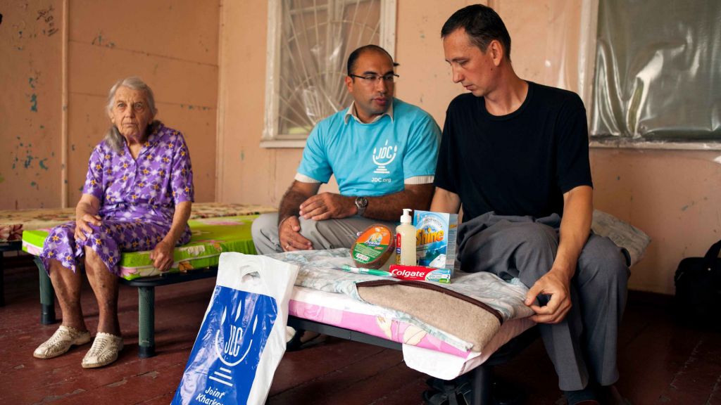 Oleg Khaet, JDC’s Kharkov welfare programs coordinator, visits a Jewish family in a refugee camp in Kharkov. He brings with him a care package with toiletries. This man and his mother were separated from his wife and children for six weeks as they fled Lugansk and are now waiting to be reunited with the help of JDC. (Rachel Calman/JDC, August 2014)