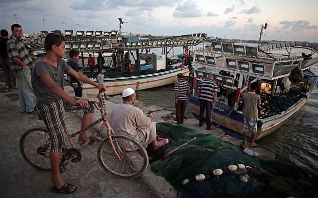 In this Saturday, Sept. 13, 2014 photo, Palestinians wait for fishermen to unload their catch so they can buy fish at the sea port of Gaza City, Gaza Strip.  (Photo credit: AP/Khalil Hamra)