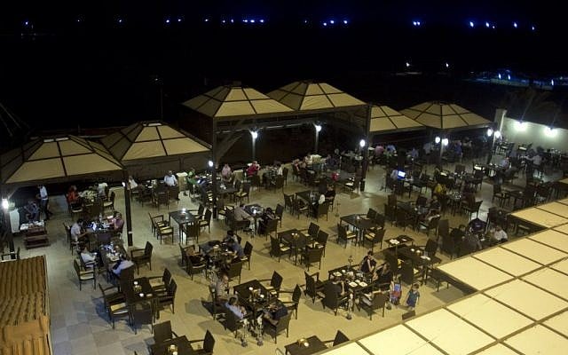 In this Sunday, Sept. 14, 2014 photo, Palestinians enjoy a summer night at a cafe by the beach of Gaza City, Gaza Strip. (Photo credit: AP/Khalil Hamra)