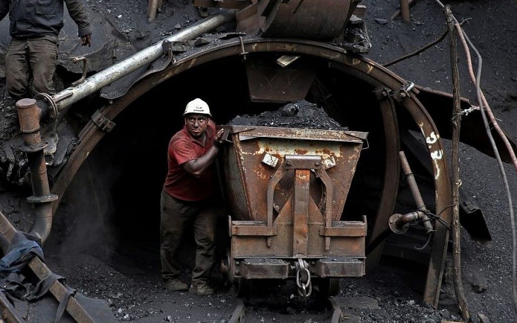 In this Monday, Aug. 18, 2014 photo, an Iranian coal miner pushes a metal cart loaded with coal.(Photo credit: AP/Ebrahim Noroozi)