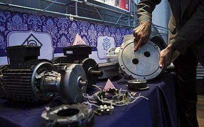 In this Monday, Sept. 1, 2014 photo, an Iranian nuclear technician shows a part of a machine of the country's nuclear facilities that Iran says was exported to the country with the alleged purpose of sabotage. (AP Photo/Vahid Salemi)