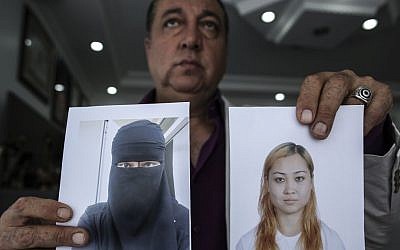 In this Friday, Sept. 19, 2014 photo, car salesman Sahin Aktan shows photos of his ex-wife Asiya Ummi Abdullah as he speaks during an interview at his lawyer's office in Istanbul, Turkey (photo credit: AP/Emrah Gurel)