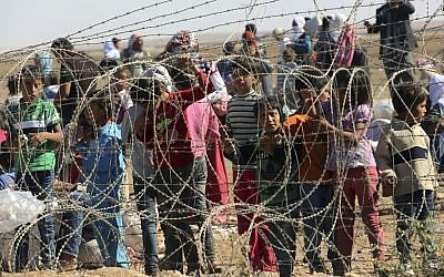 Several hundred Syrian refugees wait to cross into Turkey at the border in Suruc, Turkey, on Sunday, September 21, 2014. (photo credit: AP Photo/Burhan Ozbilici)