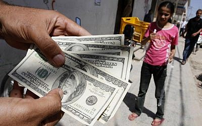 A Palestinian man employed by the PA displays the money withdrawn from an ATM at the Bank of Palestine in Rafah, southern Gaza Strip, June 8, 2012 photo credit: Abed Rahim Khatib/Flash90)