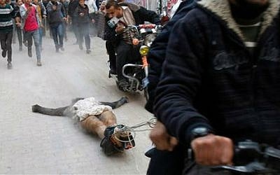 In this Nov. 20, 2012 file photo, Palestinian gunmen ride motorcycles as they drag the body of a man who was killed earlier as a suspected collaborator with Israel, in Gaza City (photo credit: AP/Adel Hana, File) 