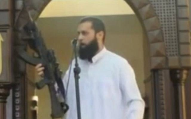 Screenshot from MEMRI video of Gaza imam brandishing rifle during a sermon on Augusyt 29, 2014.