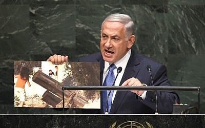 Prime Minister Benjamin Netanyahu holds up a photo of a purported Hamas rocket as he addresses the 69th Session of the UN General Assembly, September 29, 2014, in New York. (photo credit: AFP/Timothy A. Clary)