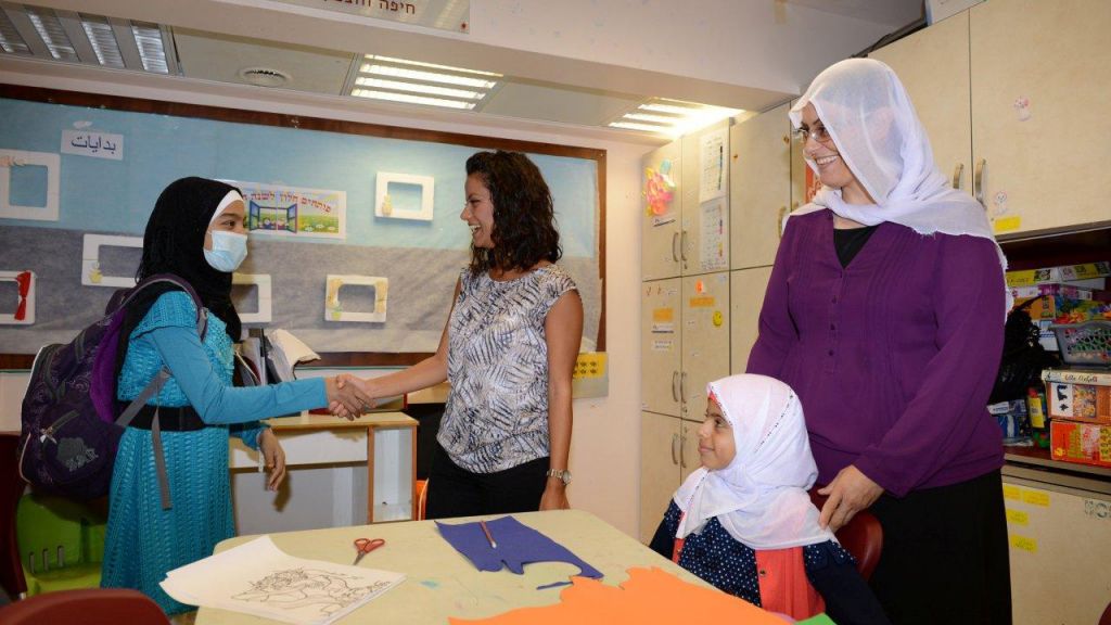 Dima Chamra, an Arab art therapist at Rambam, greets 17-year-old Sana Charoob, a patient from Jenin (left), while Amtaz Manfor, a Druze teacher at Rambam, stands behind 8-year-old patient Simdosh Chansan Jamal, also from Jenin. (photo credit: Ofer Golan) Dima Chamra, an Arab art therapist at Rambam, greets 17-year-old Sana Charoob, a patient from Jenin (left), while Amtaz Manfor, a Druze teacher at Rambam, stands behind 8-year-old patient Simdosh Chansan Jamal, also from Jenin (right). (photo credit: Ofer Golan)
