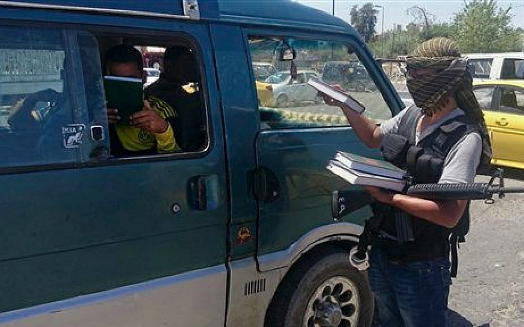 In this Sunday, June 22, 2014 file photo, a fighter from the Islamic State group, distributes a copy of the Quran to a driver in Mosul, 225 miles (360 kilometers) northwest of Baghdad, Iraq (photo credit: AP) In this Sunday, June 22, 2014 file photo, a fighter from the Islamic State group, distributes a copy of the Quran to a driver in Mosul, 225 miles (360 kilometers) northwest of Baghdad, Iraq (photo credit: AP)