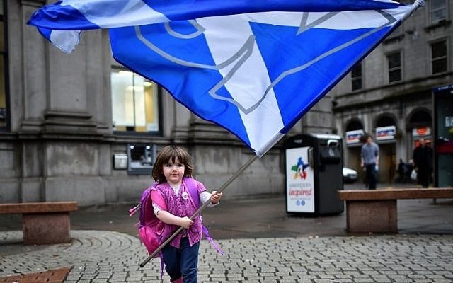 A child plays with a pro-independence 'Yes' flag on the streets of Aberdeen in Scotland, on September 15, 2014, ahead of the referendum on Scotland's independence. (photo credit: AFP PHOTO/BEN STANSALL)