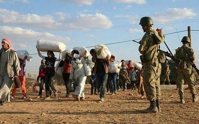Turkish soldiers stand guard as Syrian refugees gather at the border in Suruc, Turkey, late Saturday, Sept. 20, 2014. (AP) Turkish soldiers stand guard as Syrian refugees gather at the border in Suruc, Turkey, late Saturday, Sept. 20, 2014. (AP)