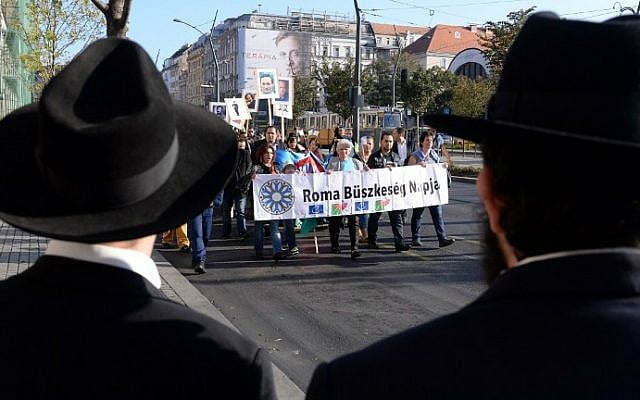 Jewish people watch local Roma and their sympathizers marching in Budapest on October 19, 2014 holding a banner that reads "Roma Pride Day;"  a demonstration against racism and discrimination that the community faces across Europe. (photo credit: Attila Kisbendek/AFP Photo)