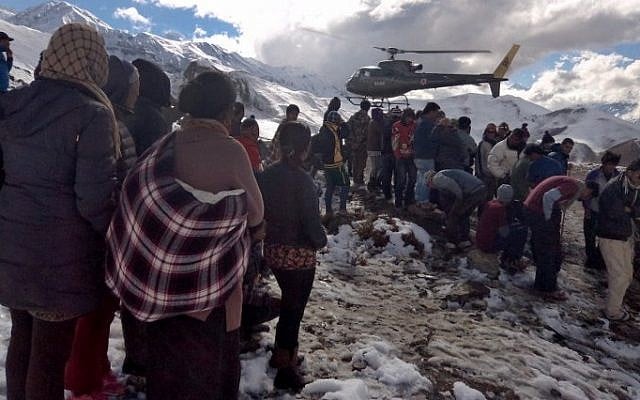 In this handout photograph released by the Nepal Army on October 15, 2014, a Nepalese Army helicopter rescues survivors of a snow storm in Manang District, along the Annapurna Circuit Trek. (Photo credit: AFP PHOTO/NEPAL ARMY)