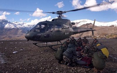 An injured survivor of a snowstorm is assisted by army personnel into a Nepalese Army helicopter in Manang District, along the Annapurna Circuit Trek, on October 15, 2014. (photo credit: AFP/Nepalese Army)