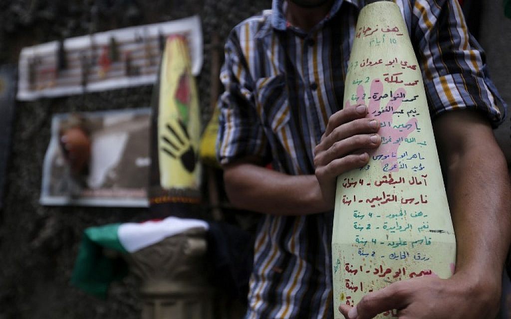 Palestinian artist Mohammed al-Zamar poses with an adorned used and diffused ammunition round on September 24, 2014, in the Bureij refugee camp in central Gaza. (photo credit: AFP Photo/Mohammed Abed)