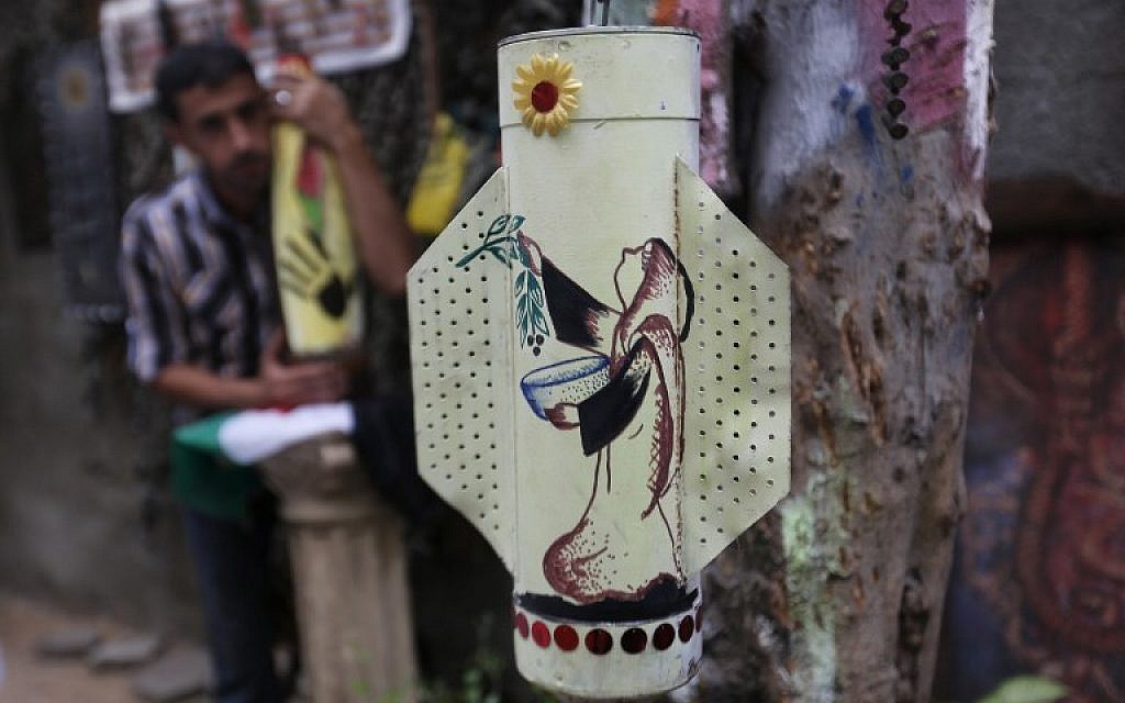 Palestinian artist Mohammed al-Zamar poses with an adorned used and diffused ammunition round on September 24, 2014, in the Bureij refugee camp in central Gaza. (photo credit: AFP Photo/Mohammed Abed)