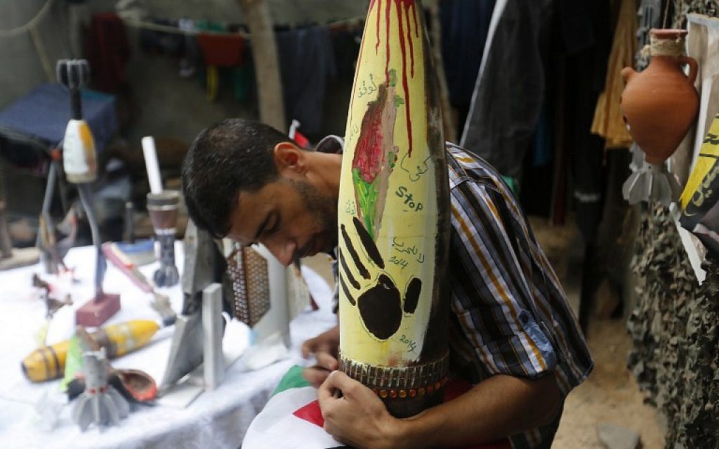 Palestinian artist Mohammed al-Zamar poses with an adorned used and diffused ammunition round on September 24, 2014, in the Bureij refugee camp in central Gaza. (photo credit: AFP Photo/Mohammed Abed)