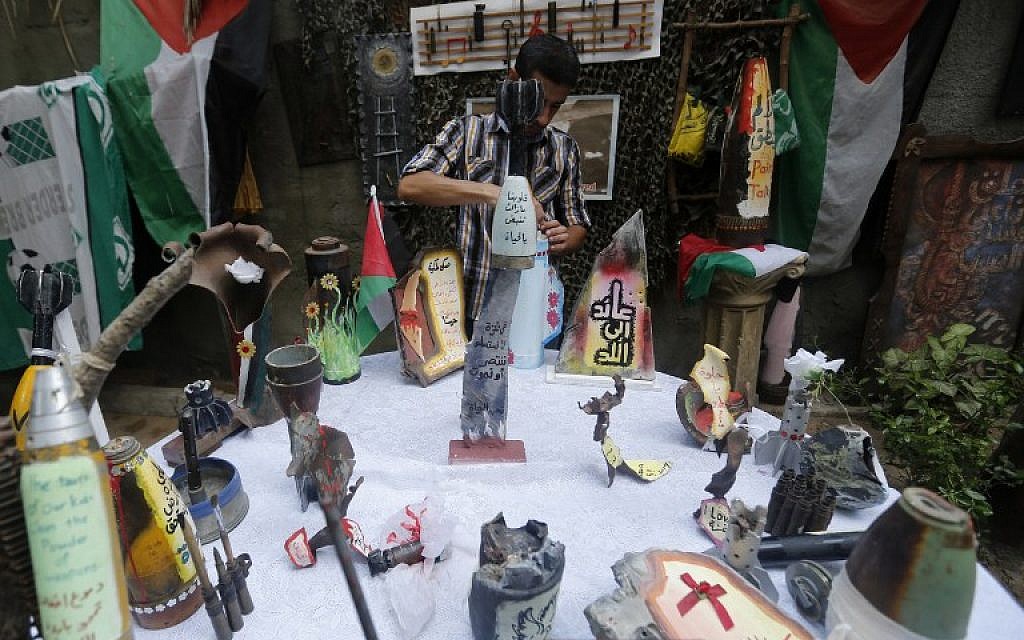 Palestinian artist Mohammed al-Zamar poses with an adorned used and diffused ammunition round on September 24, 2014, in the Bureij refugee camp in central Gaza. (photo credit: AFP Photo/Mohammed Abed)