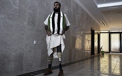 Wounded Syrian rebel Abdulkarim al-Naseef wears a scarf with symbols of the old Syrian flag, now used by the opposition, and a prosthetic leg, as he stands at a hotel lobby near Mecca's Grand Mosque on October 1, 2014 during the annual hajj pilgrimage. (AFP PHOTO/MOHAMMED AL-SHAIKH)