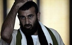 Wounded Syrian rebel Abdulkarim al-Naseef wears a scarf with symbols of the old Syrian flag, now used by the opposition, as he stands at a hotel lobby near Mecca's Grand Mosque on October 1, 2014 during the annual hajj pilgrimage. (AFP PHOTO/MOHAMMED AL-SHAIKH)