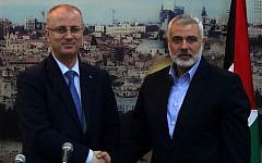 Hamas leader Ismail Haniyeh (right) shakes hands with Palestinian Authority Prime Minister Rami Hamdallah at Haniyeh's house in Gaza City, October 9, 2014.(AFP/Said Khatib)
