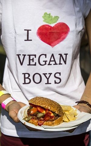 A visitor holds a plate with a vegan hamburger during the "Vegan Fest" fair on October 13, 2014, Ramat Gan Israel. (photo credit: AFP/JACK GUEZ) 