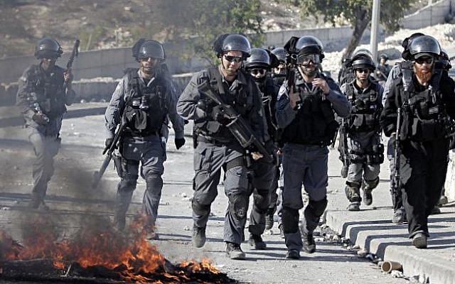Illustrative: Israeli security officers run past burning tires during clashes with Palestinian protesters in the Issawiya neighborhood in East Jerusalem on October 24, 2014. (AFP/AHMAD GHARABLI)