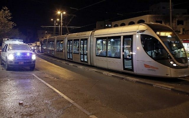 An Israeli police car drives beside light train to guard it from Palestinian stone throwers, in the East Jerusalem neighborhood of Shuafat, on October 25, 2014.  (Photo credit: AFP/ AHMAD GHARABLI)