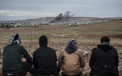 Kurdish people watch the Syrian town of Kobani, from the Turkish side of the border on October 19, 2014.  (photo credit: AFP/BULENT KILIC)