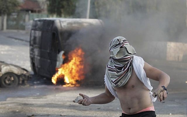 A masked Palestinian throws a rock during clashes with Israeli security forces in East Jerusalem, October 30, 2014. (photo credit: AFP/Ahmad Gharabli)