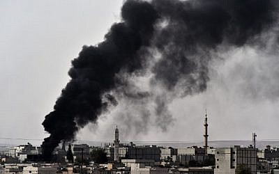 The village of Mursitpinar with smoke rising from the Syrian town of Ain al-Arab, known as Kobani by the Kurds, on October 10, 2014. (photo credit: AFP/Aris Messinis)