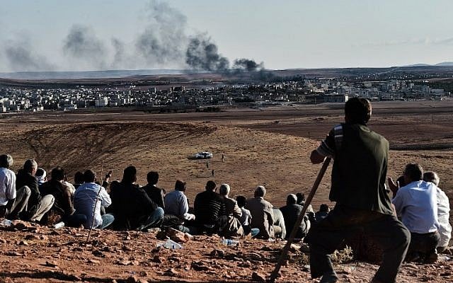 Kurdish people watch smoke billowing from Kobani as they gather upon a hill overlooking the Syrian town of Kobani, also known as Ain al-Arab, in the southeastern village of Mursitpinar, Sanliurfa province, on October 15, 2014. (photo credit: AFP/ ARIS MESSINIS) Kurdish people watch smoke billowing from Kobani as they gather upon a hill overlooking the Syrian town of Kobani, also known as Ain al-Arab, in the southeastern village of Mursitpinar, Sanliurfa province, on October 15, 2014. (photo credit: AFP/ ARIS MESSINIS)