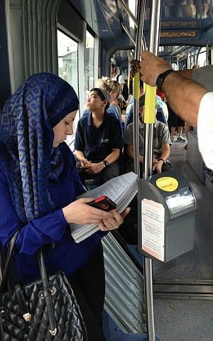 A Palestinian student reads her textbook on the light rail at Shuafat, Jerusalem, September 30, 2014 (photo credit: Elhanan Miller / Times of Israel)