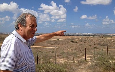 Kibbutz Nir Am resident Micha Ben Hillel points at Gaza from a mound outside his community (photo credit: Elhanan Miller/Times of Israel)