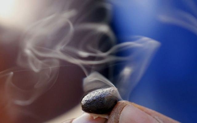 A worker inspects the crystalline resin powder "extracted hash" by fire in his hand in the Village of Bni Ahmed in the Ketama Abdelghaya valley, northern Morocco, on September 14, 2014. (photo credit: AP Photo/Abdeljalil Bounhar)