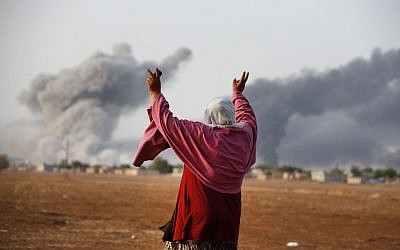 A Syrian Kurd gestures as thick smoke rises following an airstrike by the US-led coalition in Kobani, on Monday, October 13, 2014. (photo credit: AP Photo/Lefteris Pitarakis)