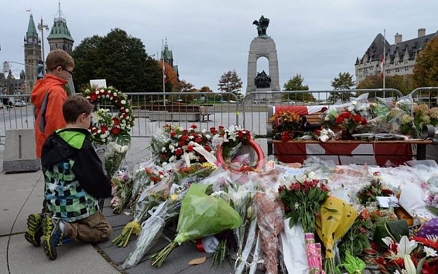 Two boys lay floral tributes for Cpl. Nathan Cirillo at the National War Memorial in Ottawa on Thursday, Oct. 23, 2014. Canadians are mourning the loss of Cpl. Nathan Cirillo, the army reservist who was shot dead as he stood guard before the Tomb of the Unknown soldier on Wednesday. Flags were flown at half-staff to honor Cirillo, a 24-year-old a reservist from Hamilton, Ontario, whose shooting on Wednesday began an attack that ended with a lone gunman storming into Parliament and opening fire before being shot dead himself. (photo credit: AP Photo/The Canadian Press, Sean Kilpatrick) Two boys lay floral tributes for Cpl. Nathan Cirillo at the National War Memorial in Ottawa on Thursday, Oct. 23, 2014. Canadians are mourning the loss of Cpl. Nathan Cirillo, the army reservist who was shot dead as he stood guard before the Tomb of the Unknown soldier on Wednesday. Flags were flown at half-staff to honor Cirillo, a 24-year-old a reservist from Hamilton, Ontario, whose shooting on Wednesday began an attack that ended with a lone gunman storming into Parliament and opening fire before being shot dead himself. (photo credit: AP Photo/The Canadian Press, Sean Kilpatrick)